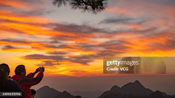 Tourist takes a photo of the sunrise scenery of the Mount Huangshan Scenic Area on May 29, 2023 in Huangshan city, Anhui Province of China.