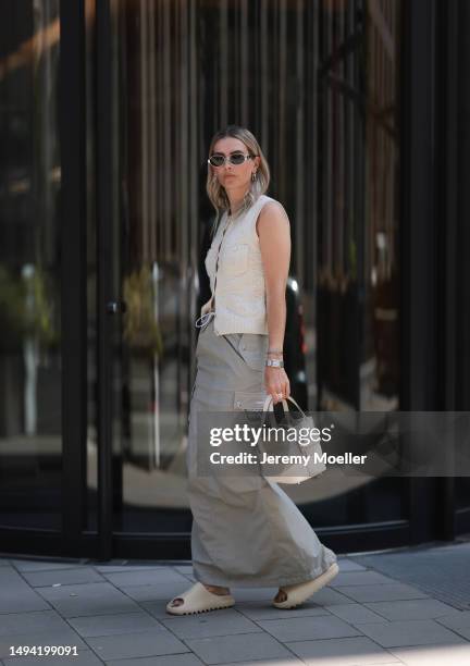 Kathrin Bommann wearing Adidas Yeezy beige rubber slides, Celine chrome silver oval shades, Chanel beige vest knit vintage top, Hermes Picotin beige...