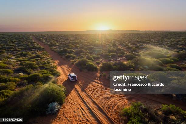 australia on the road. aerial view - dirt road landscape sunset stock-fotos und bilder