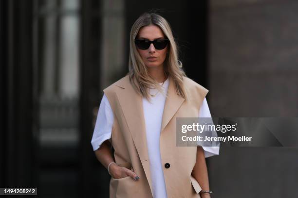 Kathrin Bommann wearing Kassel long beige vest coat, Vival Studio white oversized shirt dress, Saint Laurent black shades, Hermes vintage black...