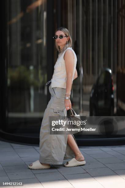 Kathrin Bommann wearing Adidas Yeezy beige rubber slides, Celine chrome silver oval shades, Chanel beige vest knit vintage top, Hermes Picotin beige...