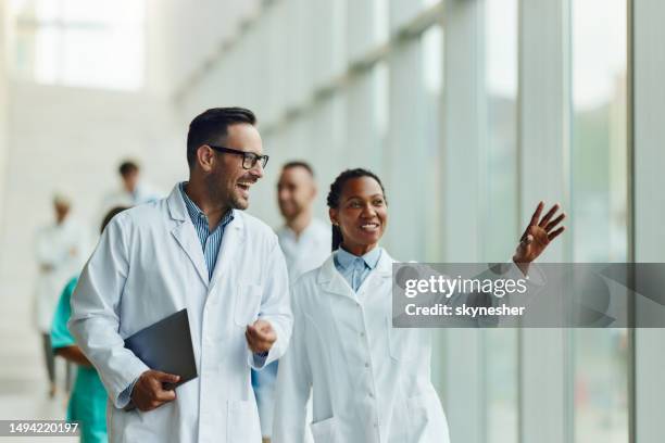 glückliche ärzte, die durch den flur eines krankenhauses gehen. - laborkittel stock-fotos und bilder