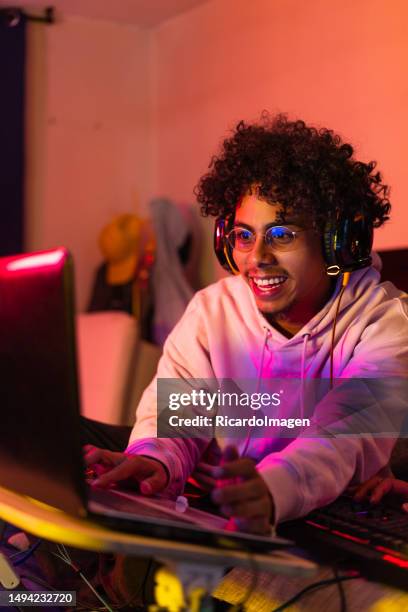 il giocatore sta giocando a un videogioco dal suo laptop in camera da letto - scrittura latina foto e immagini stock