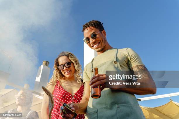 spanish group of millennial people cooking a barbecue birthday party outdoors laughing at summer time - bbq apron stock pictures, royalty-free photos & images