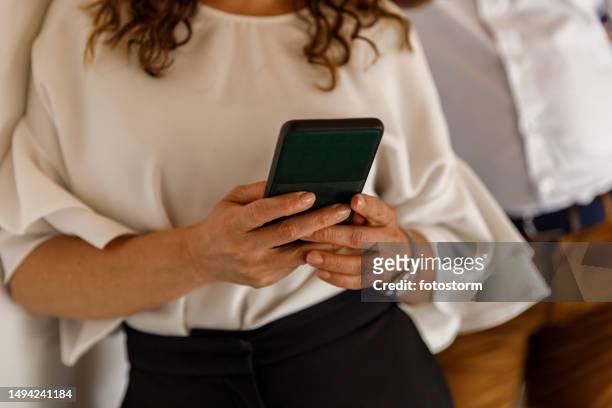 midsection of woman using her smart phone while waiting in line - facebook check in stock pictures, royalty-free photos & images
