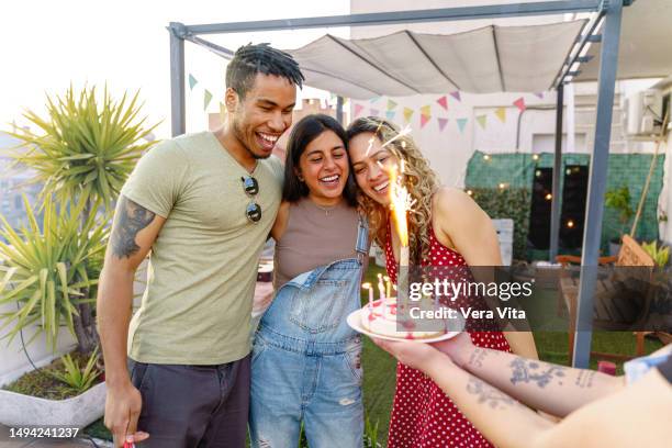 multiracial young group of friends at terrace together celebrating with sparkling lights a summer birthday party - birthday party friends stock pictures, royalty-free photos & images