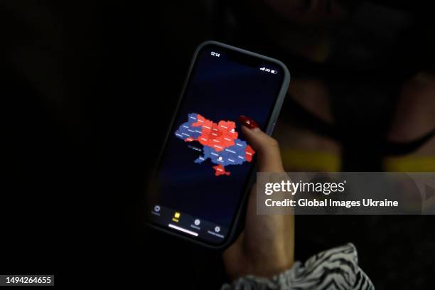 Woman holds her telephone with map of air alerts in Ukraine in a metro station on May 29, 2023 in Kyiv, Ukraine. During the day, Russian troops...