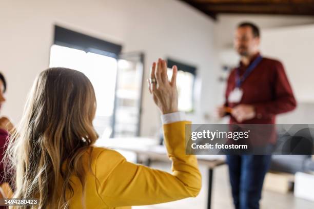businesswoman raising her hand to ask a question during a group meeting - the lift presented stock pictures, royalty-free photos & images