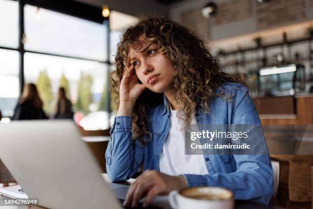 müde und besorgte frau, die in einem café am laptop arbeitet - bedauern stock-fotos und bilder