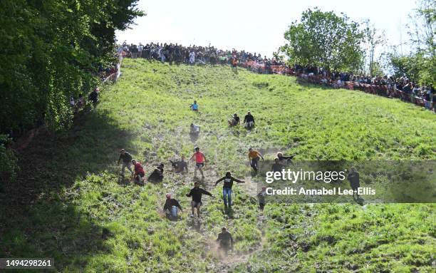Participants take part in one of the Cooper's hill downhill cheese rolling races on May 29, 2023 in Gloucester, United Kingdom. This year, with no...