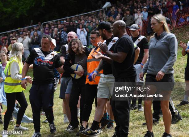 The winner of the first Cooper's hill women's downhill race smiles with her cheese and supporters after being knocked unconscious during the race on...