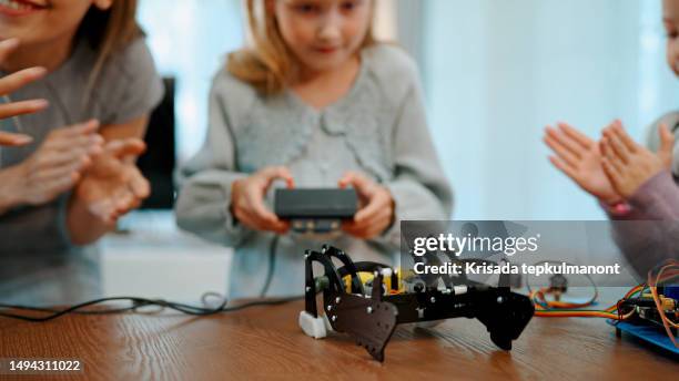 young schoolgirl controlling electronic robot under teacher's guidance. - playroom stock pictures, royalty-free photos & images