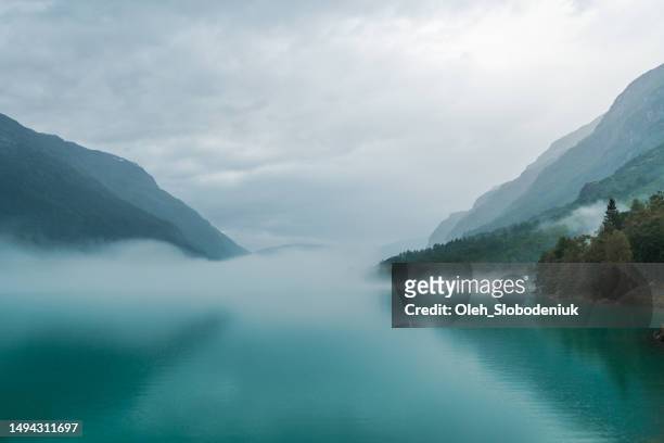scenic view of lake in norway covered in fog - serenity stockfoto's en -beelden