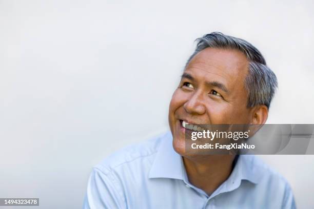 portrait of asian chinese mixed race senior mature man in collared business shirt smiling looking upward - portrait white background looking away stockfoto's en -beelden