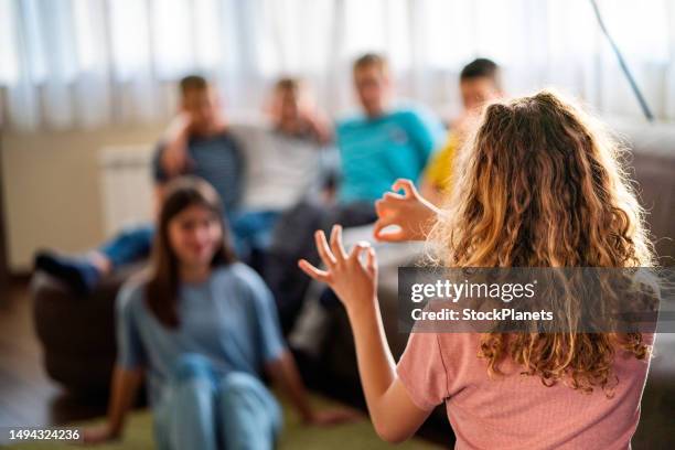 rückansicht einer gruppe von kindern, die zu hause scharade spielen - pantomime stock-fotos und bilder