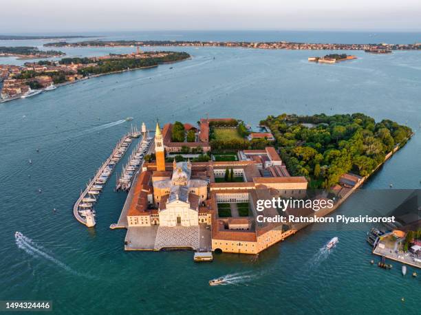 aerial drone sunrise scene of the venice islands church of san giorgio maggiore and traffic of boat between blue water of the lagoon opposite the piazzetta di san marco, 16th century benedictine church on the island of the same name in venic - santa maria della salute stock pictures, royalty-free photos & images