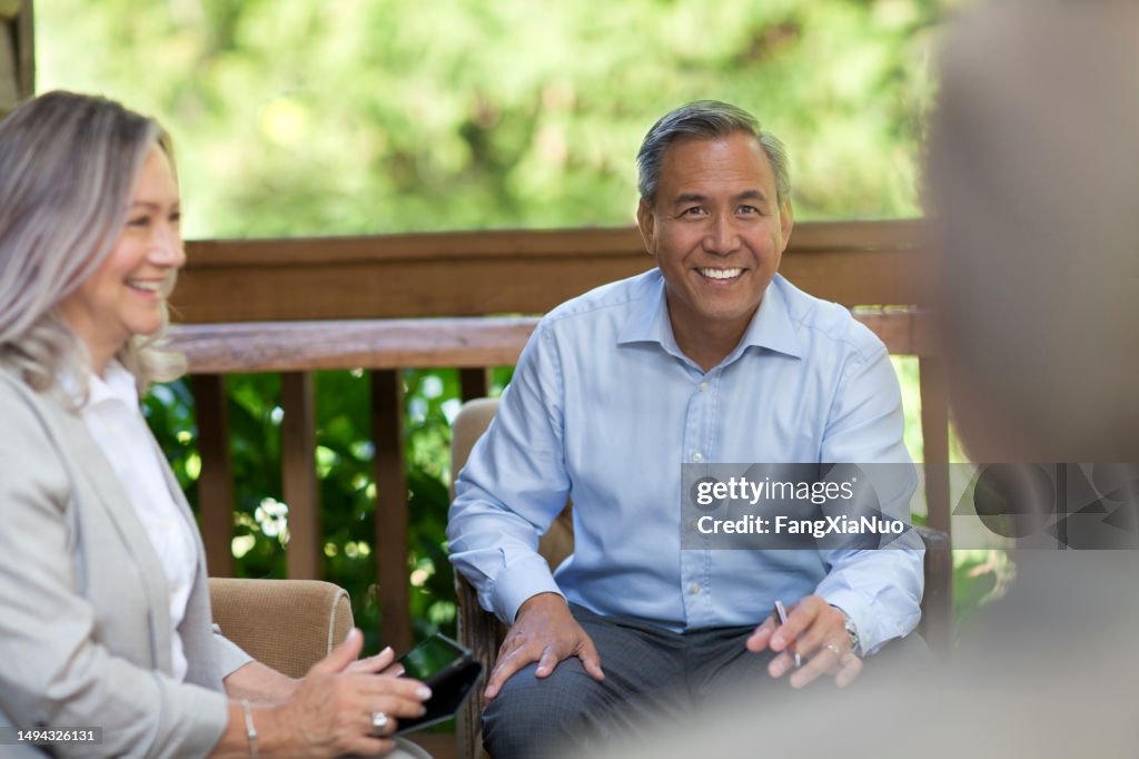 Mature senior Asian Chinese multiracial businessman collaborating and discussing ideas with coworker colleagues in business meeting at corporate retreat