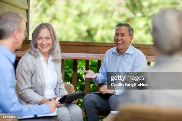 mature senior business colleagues collaborating and discussing ideas in meeting at corporate retreat with coworkers - retreating stock pictures, royalty-free photos & images