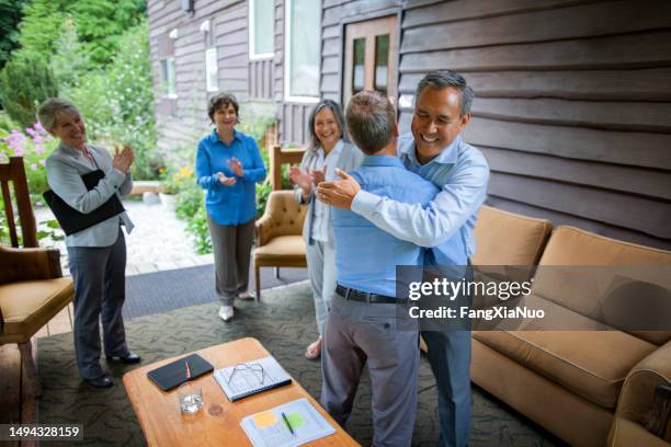mature senior businessmen colleagues collaborating and discussing ideas in meeting at corporate retreat with coworkers embracing congratulating success - succession planning stock pictures, royalty-free photos & images