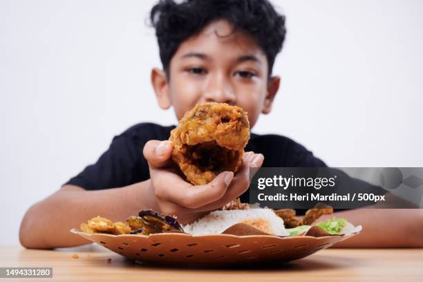 cheerful boy eating fried fish and rice at home,bali,indonesia - heri mardinal stock pictures, royalty-free photos & images