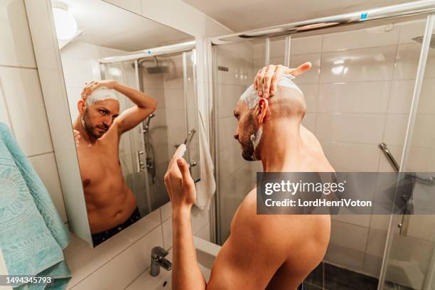 man applying shaving cream in front of the mirror - head shave stockfoto's en -beelden