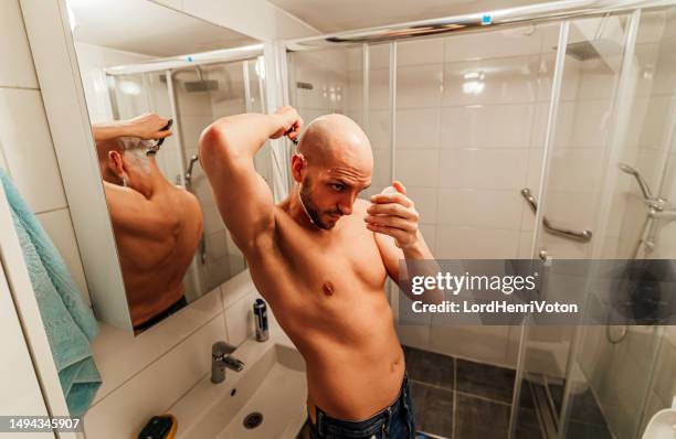 young man shaving his head in the bathroom - shaving head stock pictures, royalty-free photos & images