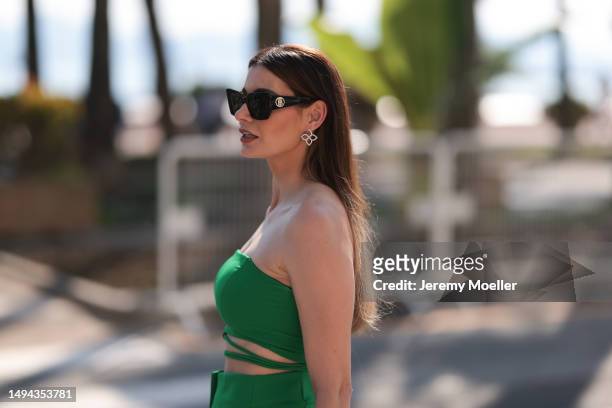 Film Festival Guest seen wearing a green two piece, black YSL handbag with a Hermes clotch and black heels and Burberry shades during the 76th Cannes...
