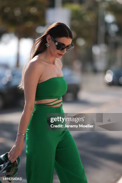 Film Festival Guest seen wearing a green two piece, black YSL handbag with a Hermes clotch and black heels and Burberry shades during the 76th Cannes...