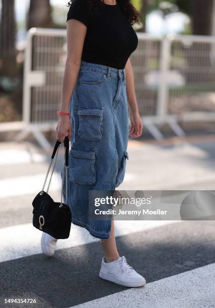 Film Festival Guest is seen wearing a blue denim long jeans skirt, black shirt, white Nike sneaker, black shades and black leather handbag during the...