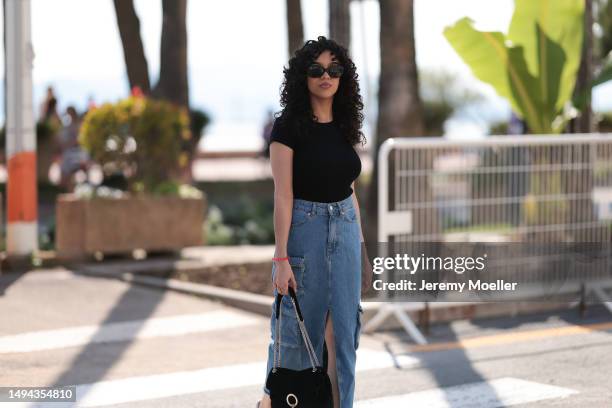 Film Festival Guest is seen wearing a blue denim long jeans skirt, black shirt, white Nike sneaker, black shades and black leather handbag during the...