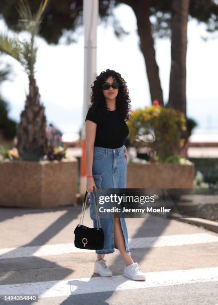 Film Festival Guest is seen wearing a blue denim long jeans skirt, black shirt, white Nike sneaker, black shades and black leather handbag during the...