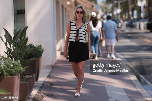 Jo Wallter is seen wearing a white and black stripped top, black shorts, white Hermes sandals and black shades and a Dior saddlebag during the 76th...