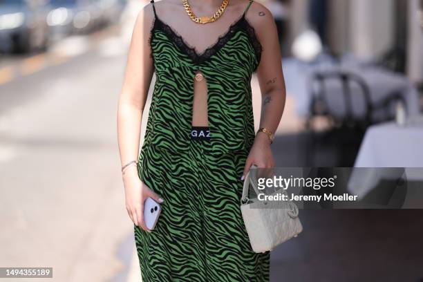 Film Festival Guest is seen wearing a green and black printed matchy two piece, black shades and a creme Lady Dior bag during the 76th Cannes film...