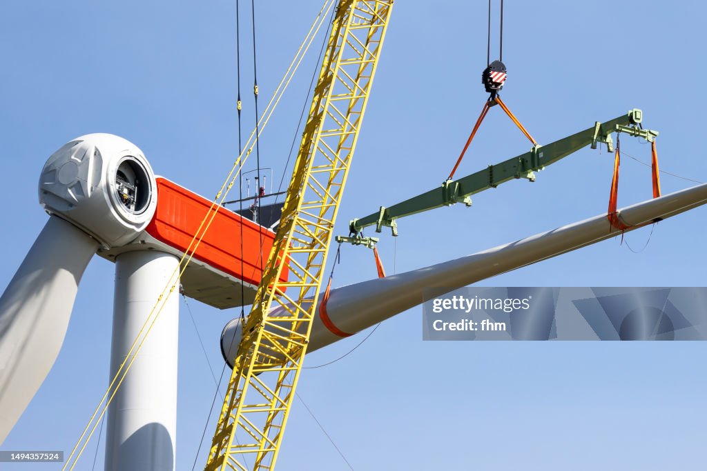 Wind Turbine Construction Site Crane Lifts A Rotor Blade To The wind-turbine-construction-site-crane-lifts-a-rotor-blade-to-the