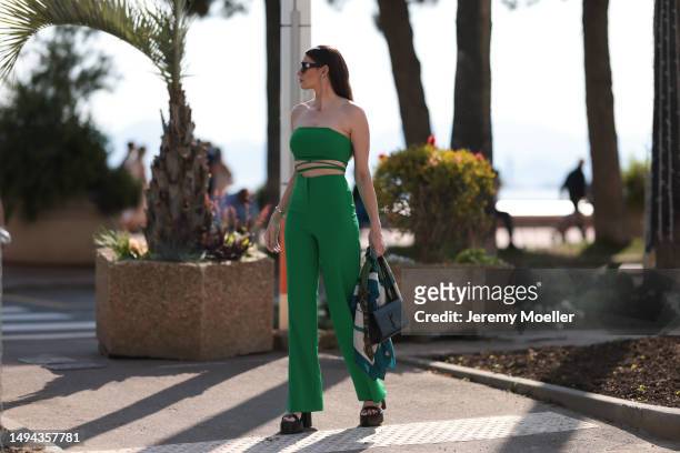 Film Festival Guest seen wearing a green two piece, black YSL handbag with a Hermes clotch and black sandals heels and Burberry shades during the...