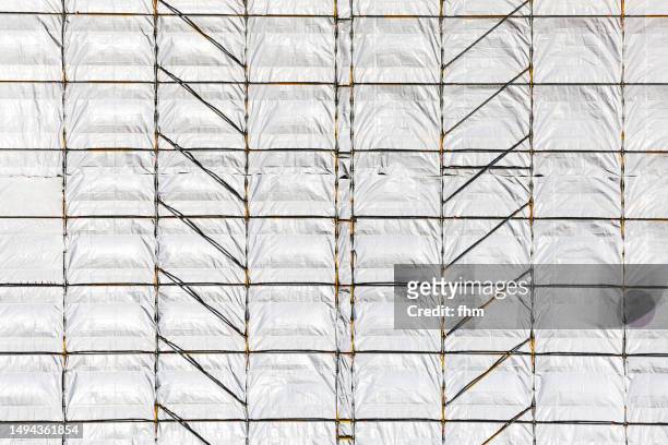 scaffolding at a construction site - dekzeil stockfoto's en -beelden