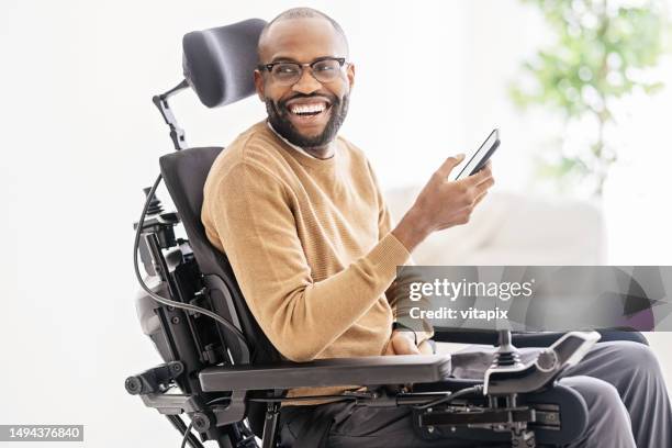 disabled black man using smartphone at home - estacionamento restrito imagens e fotografias de stock