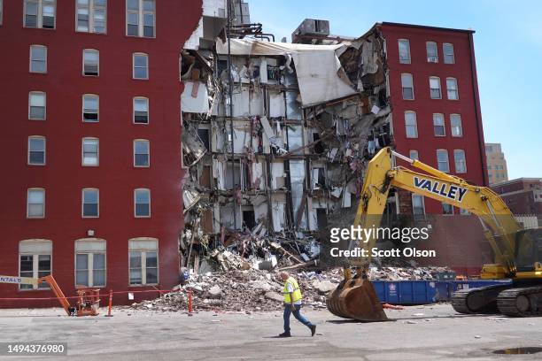 Worker walks by a six-story apartment building after it collapsed yesterday on May 29, 2023 in Davenport, Iowa. Eight people were rescued from the...