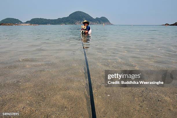 Japanese man and his pet dog bath in the water at Takeno Beach on July 28, 2012 in Toyooka, Japan. This beach is especially open for dogs and their...