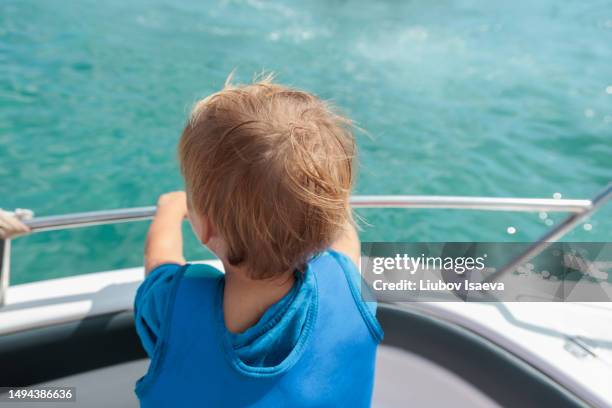 back view of little boy (3-4 years) in life vest enjoying boat trip in the open sea. - 2 3 years foto e immagini stock