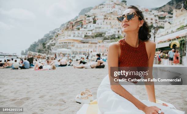 a beautiful woman enjoys lounging on a beach in positano, italy - handdoek stockfoto's en -beelden