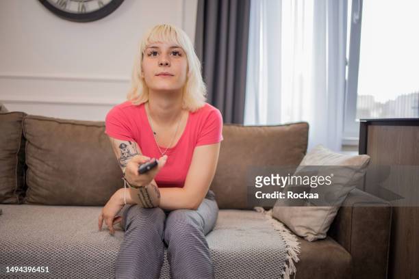 woman enjoying her favorite tv show at home - tv show stockfoto's en -beelden