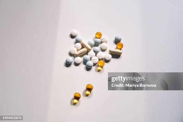 a handful of tablets, vitamins and trace elements on a light background. - vitamin a stock pictures, royalty-free photos & images