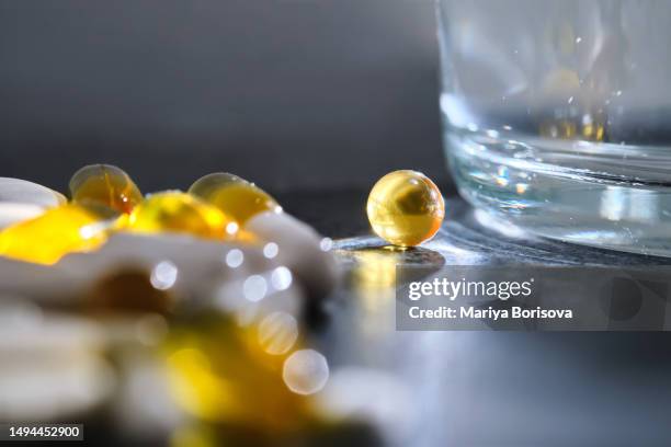 tablets, vitamins and dietary supplements on a dark table next to a glass of water. - se stock pictures, royalty-free photos & images