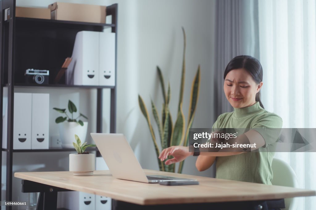 Asian woman irritate itching dry skin scratching her skin sitting at home office.