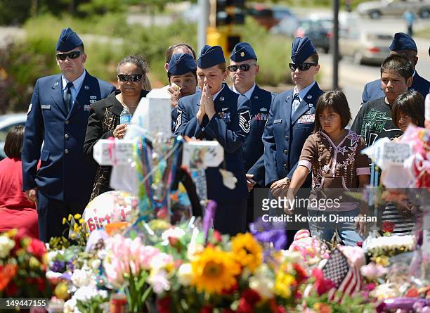Air Force Senior Master Sgt. Raea Thompson , from nearby Buckley Air Force base, prays as she and her fellow servicemen visit theater shooting victim...