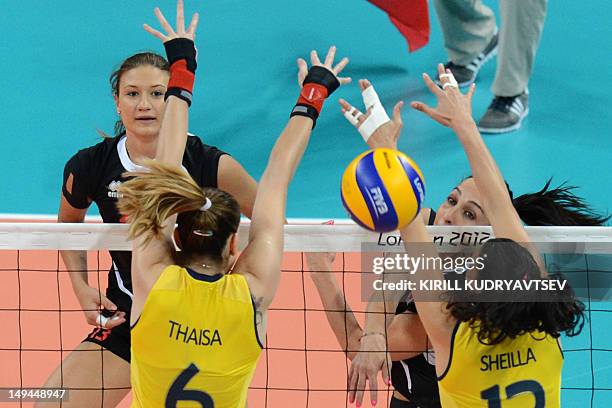 Turkey's Gozde Sonsirma spikes as Brazil's Sheilla Castro and Thaisa Menezes attempts to block during the women's volleyball match between Turkey and...
