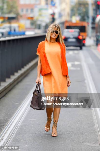 Influencer Gitta Banko, wearing a light orange colored knitted dress by Iris von Arnim, a orange jacket by Wommelsdorf, sandals by Tom Ford, a brown...