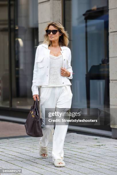 Influencer Gitta Banko, wearing white pants by Gitta Banko, a white top by Roberto Collina, a white jacket by Barrie, beige shag sandals by Prada, a...