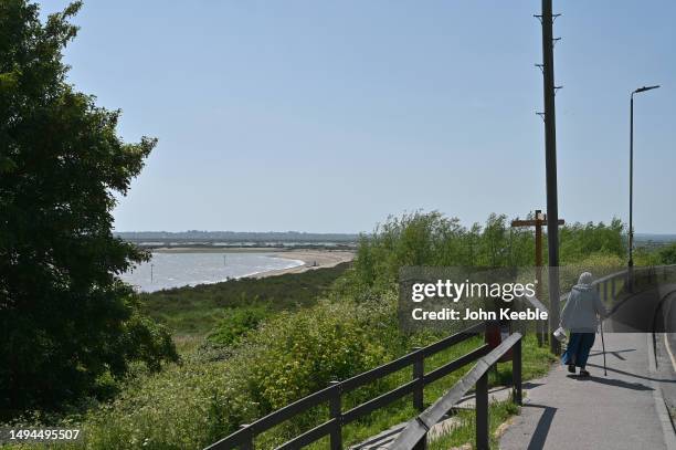 An elderly woman walks along the Coast Road with a view of the Beach in West Mersea on May 27, 2023 in Mersea Island, England.